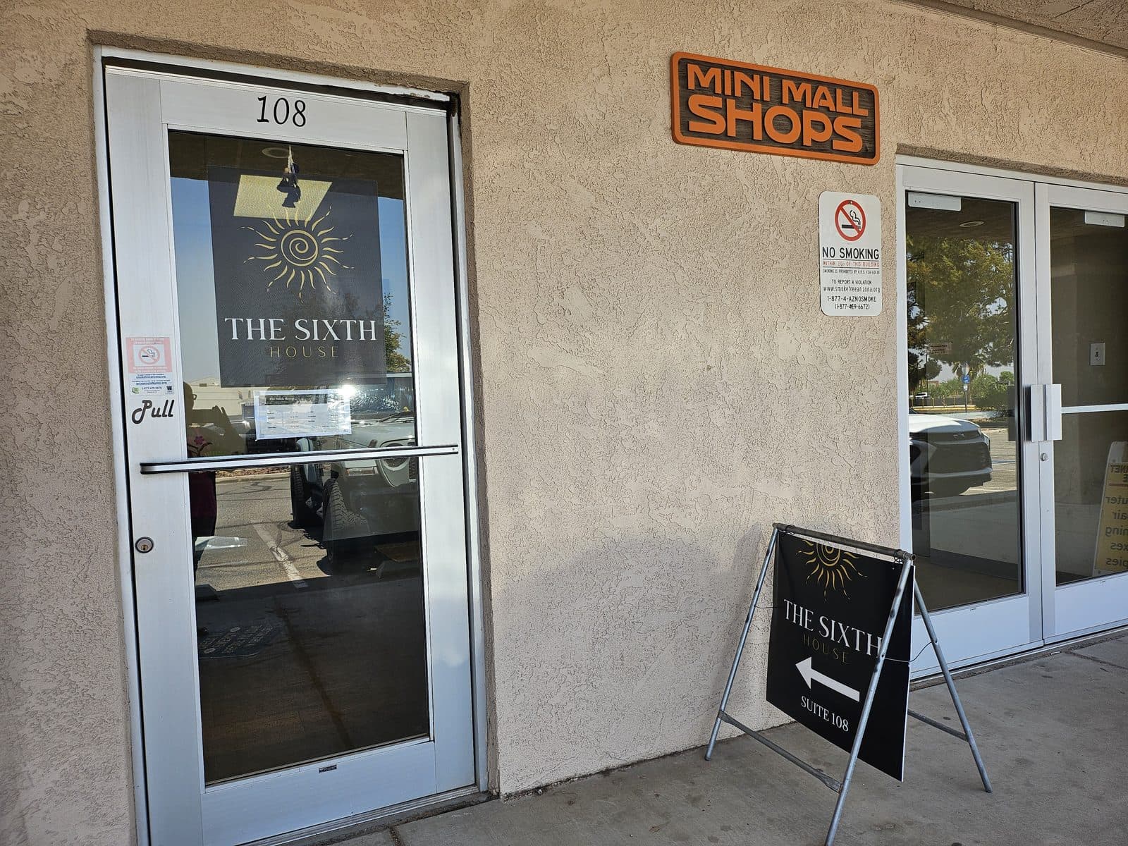 The Suite 108 entrance to The Sixth House with an A-frame sign on the walkway.